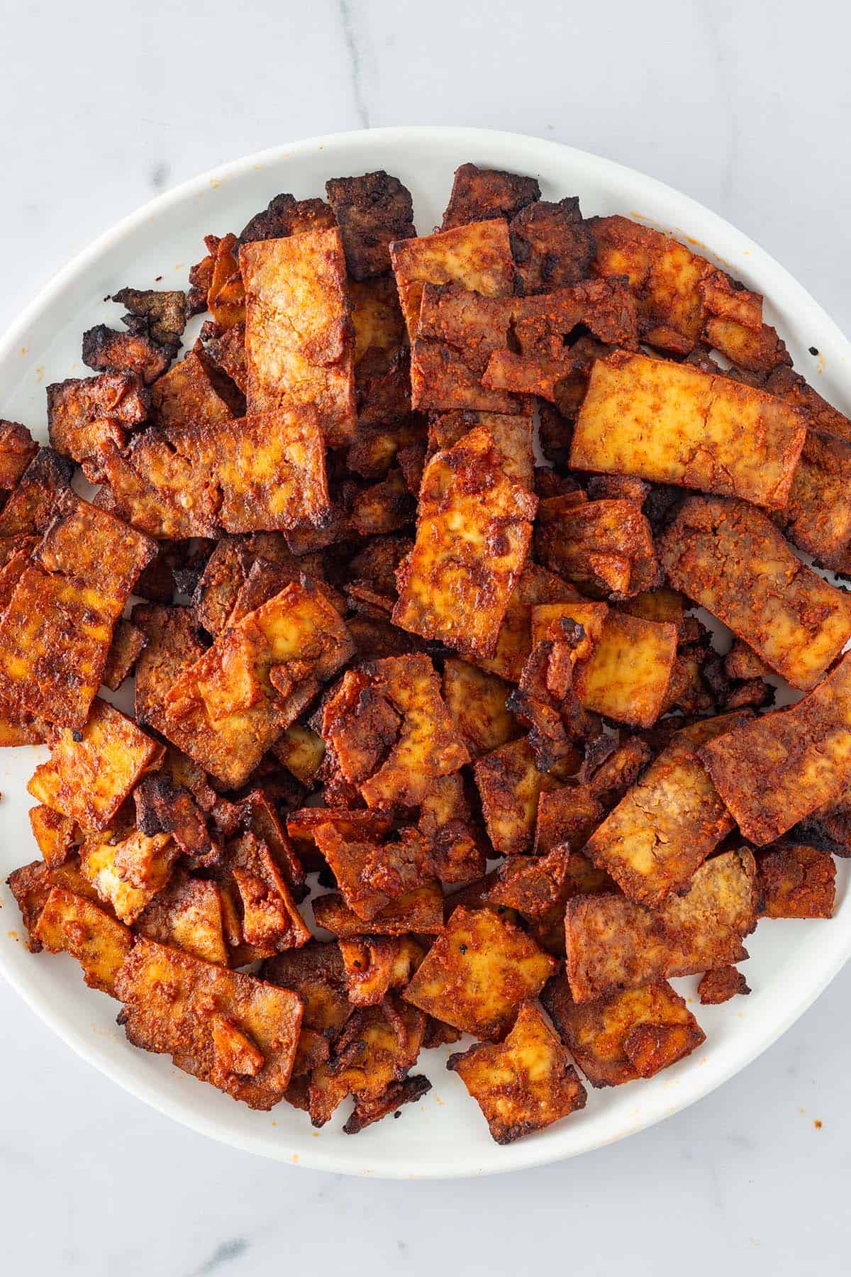 Knusprig gebackene Tofu-Gyros-Streifen auf einem wei&szlig;en Teller.