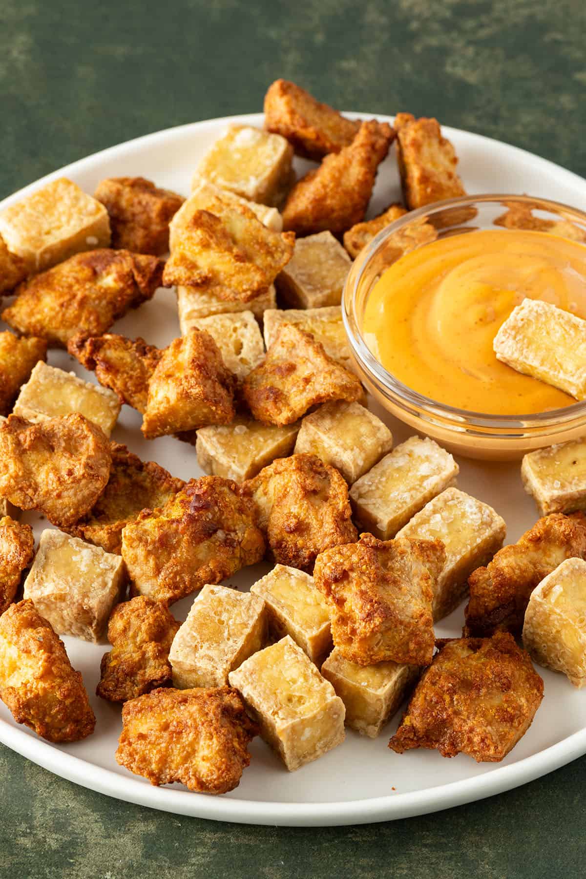 Knusprige Tofuw&uuml;rfel mit und ohne Marinade aus der Hei&szlig;luftfritteuse auf einem Teller mit Dip.
