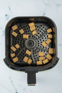 Knusprig gebackene Tofu-W&uuml;rfel im Airfryer-Korb.