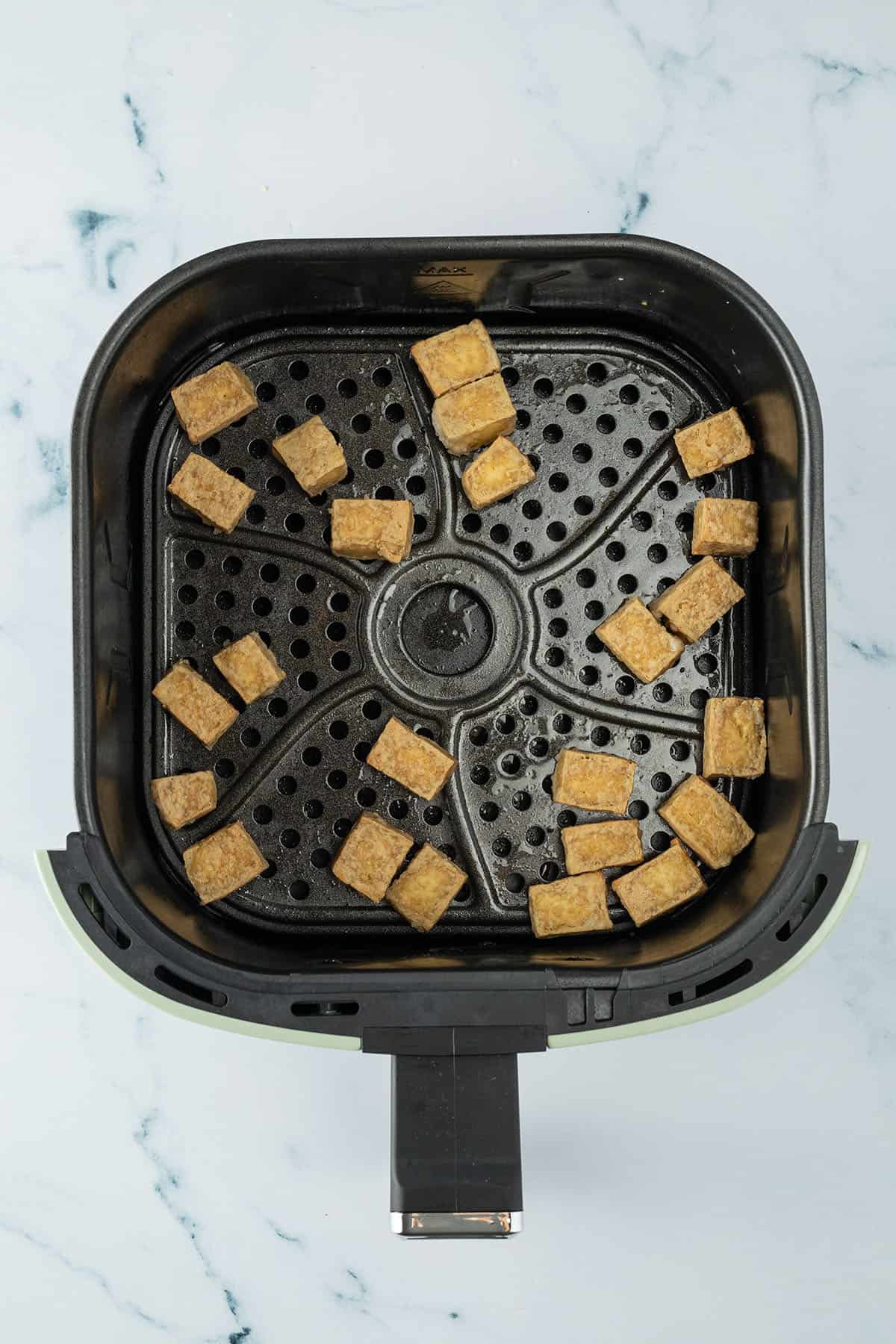 Knusprig gebackene Tofu-W&uuml;rfel im Airfryer-Korb.