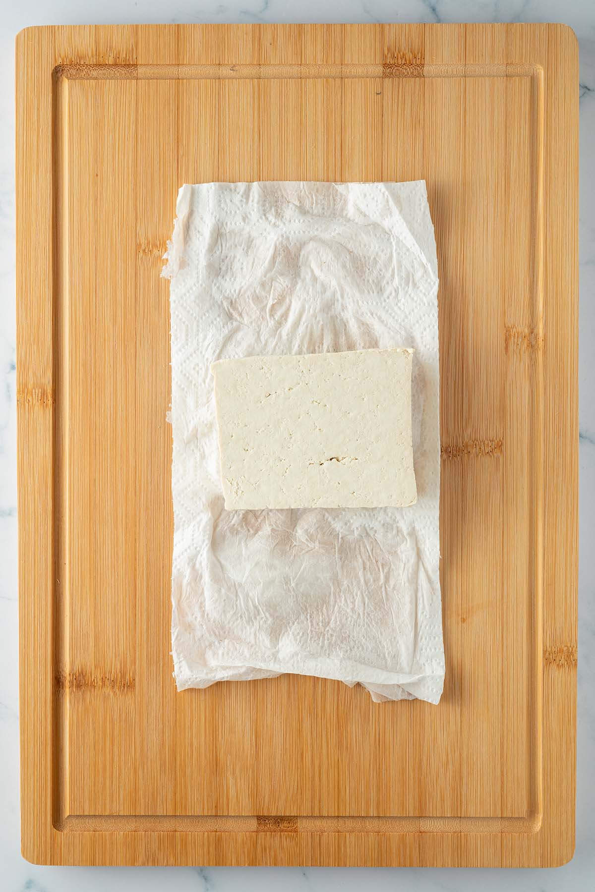 Ein Block Tofu wurde auf etwas K&uuml;chenrolle ausgepresst.