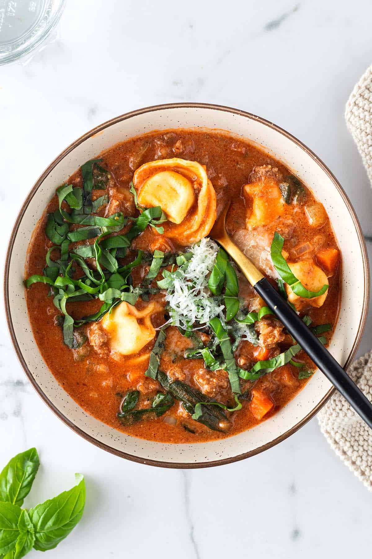 Sch&uuml;ssel mit cremiger Tortellini Suppe auf hellem Untergrund.
