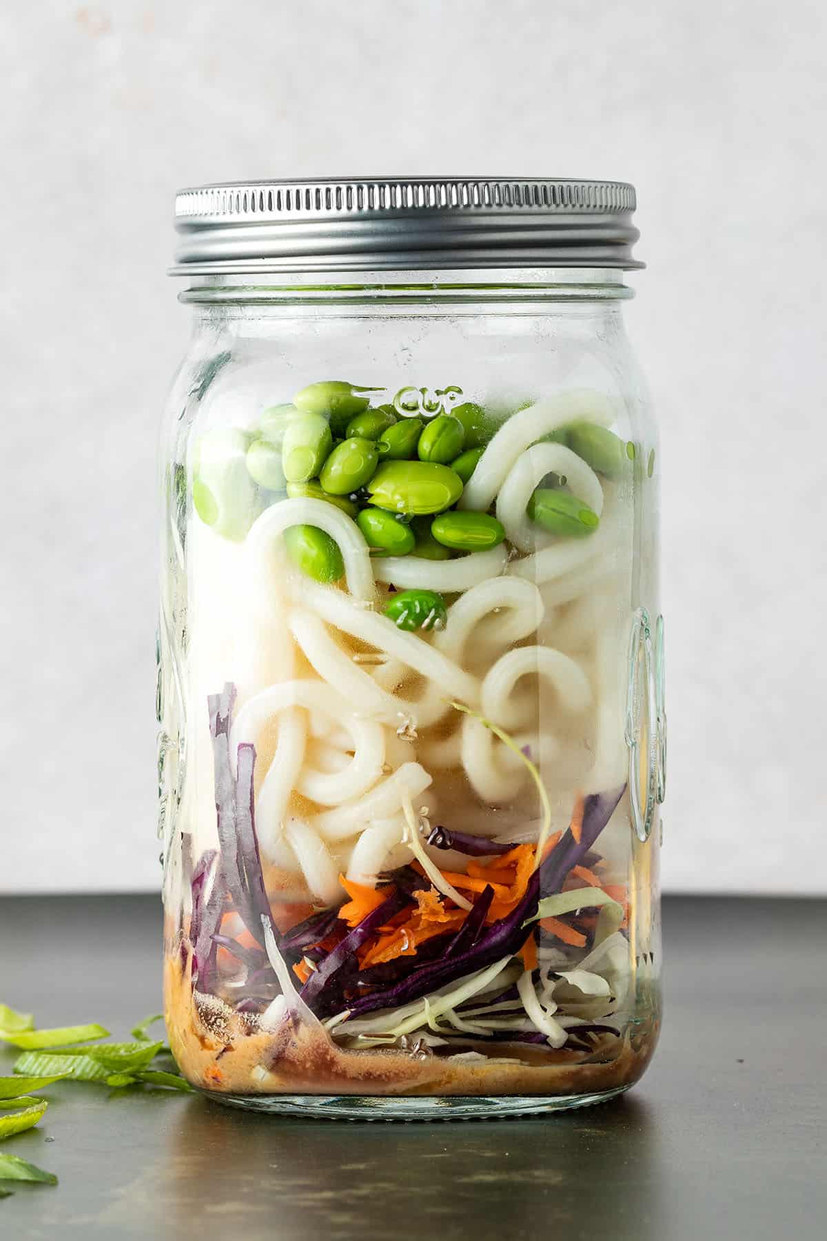 Asiatischer Nudelsalat in einem gro&szlig;en Schraubglas geschichtet.