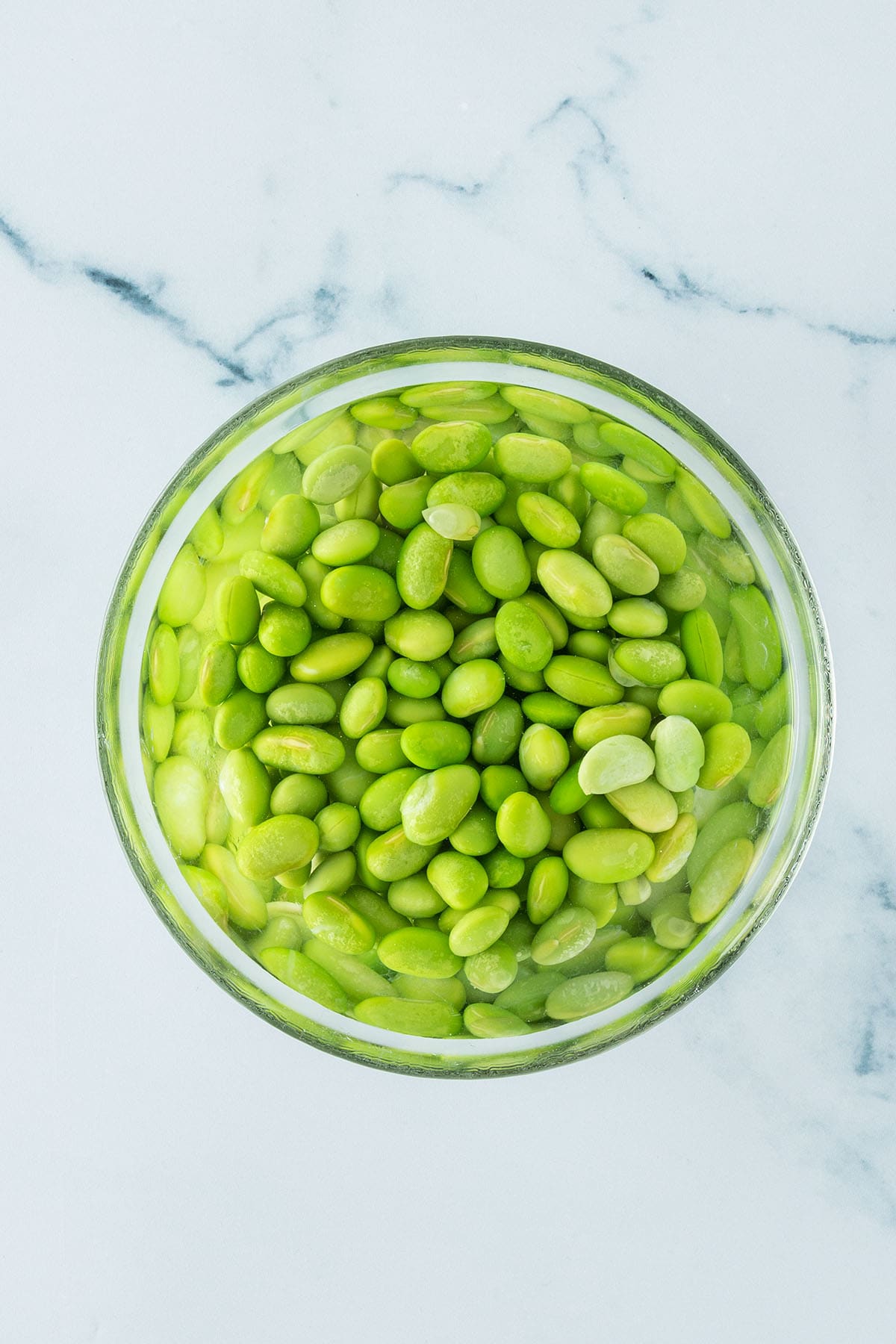 Gesch&auml;lte Edamame Bohnen in einer Sch&uuml;ssel mit Wasser.