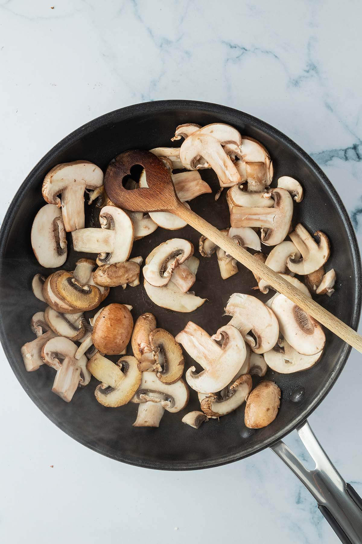 Angebratene Champignons in einer Pfanne.