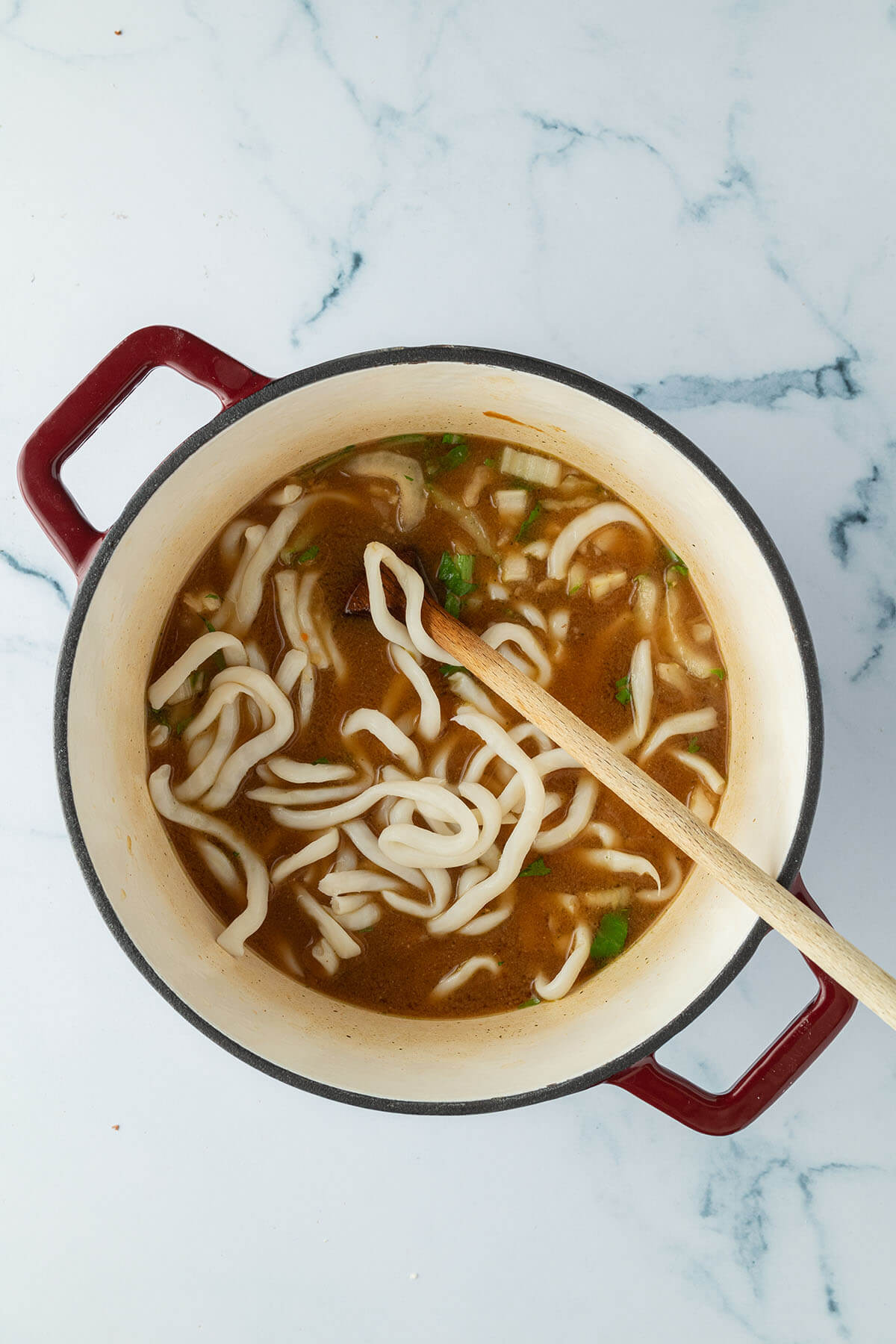 Vogelperspektive auf einen Topf mit Udon Nudeln und Pak Choi in einer Miso Br&uuml;he.