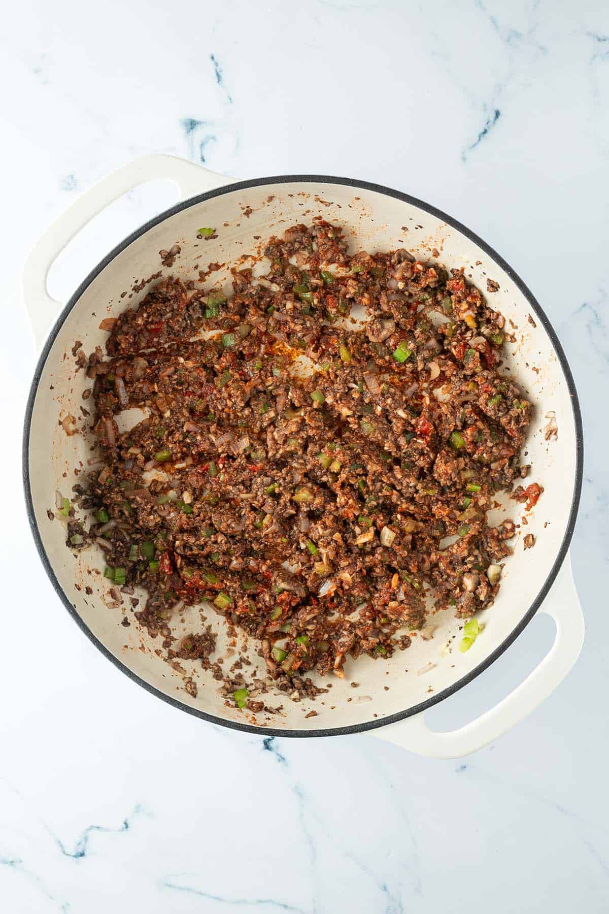 Fein zerkleinerte Champignons werden in einer Pfanne mit Tomatenmark und Gem&uuml;se angebraten.