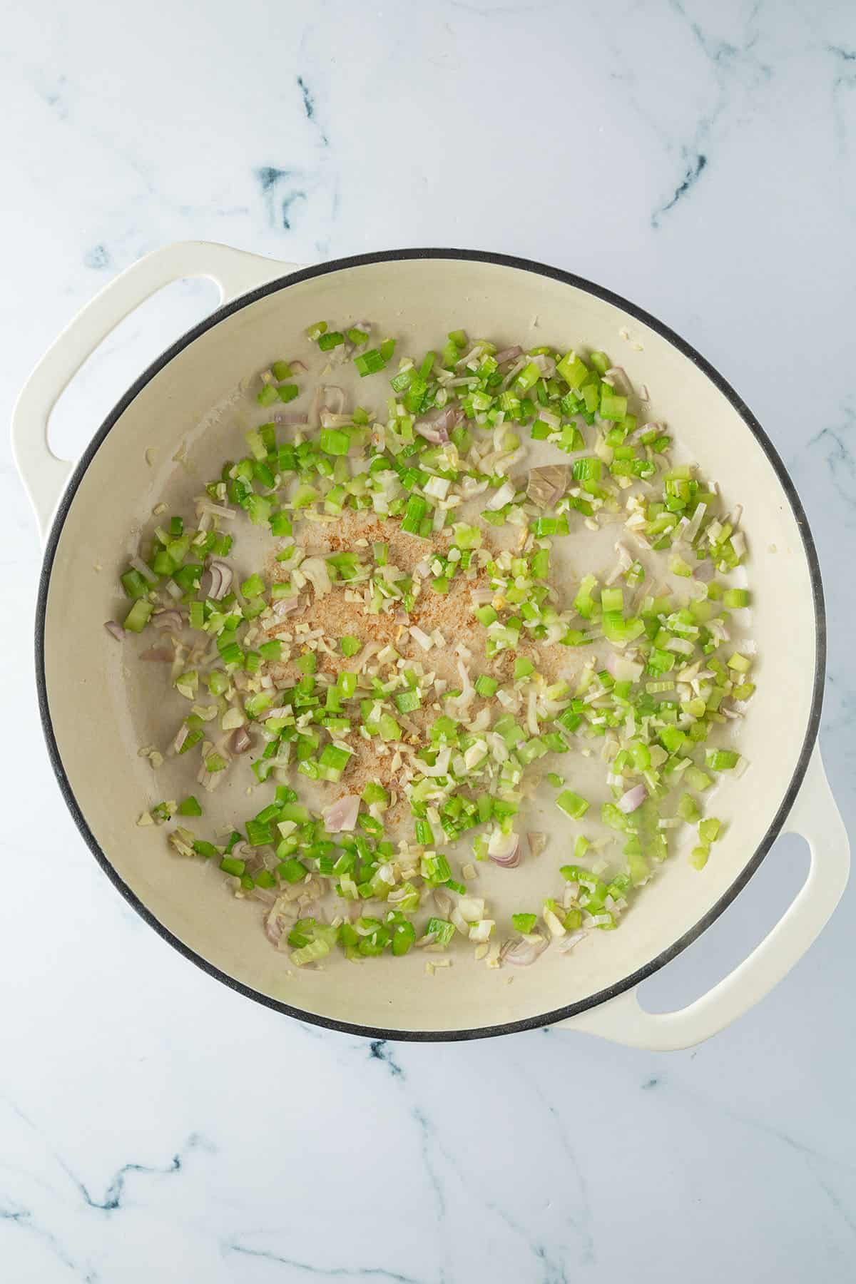 Gem&uuml;se wird in einer gro&szlig;en Pfanne angebraten.