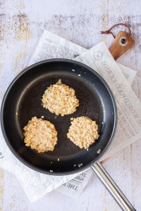 Drei vegetarische Frikadellen werden in einer Pfanne angebraten.
