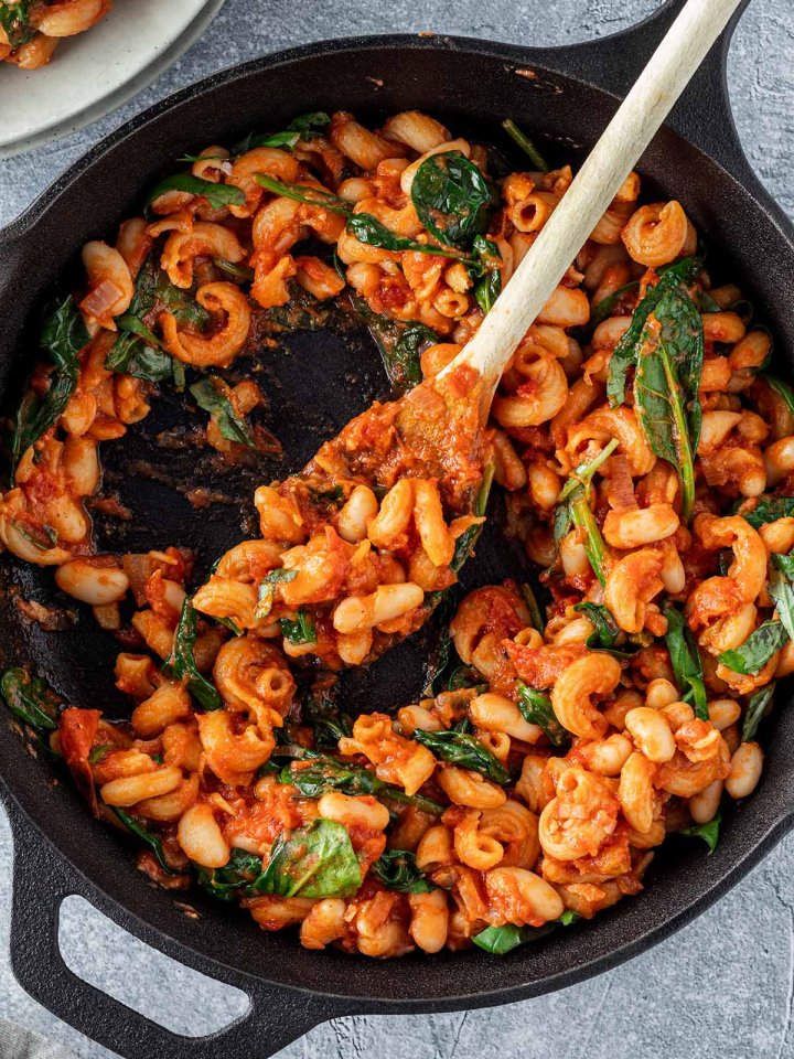Vogelperspektive auf eine Gusseisenpfanne, aus der gerade eine Portion der One Pot Pasta entnommen wird.