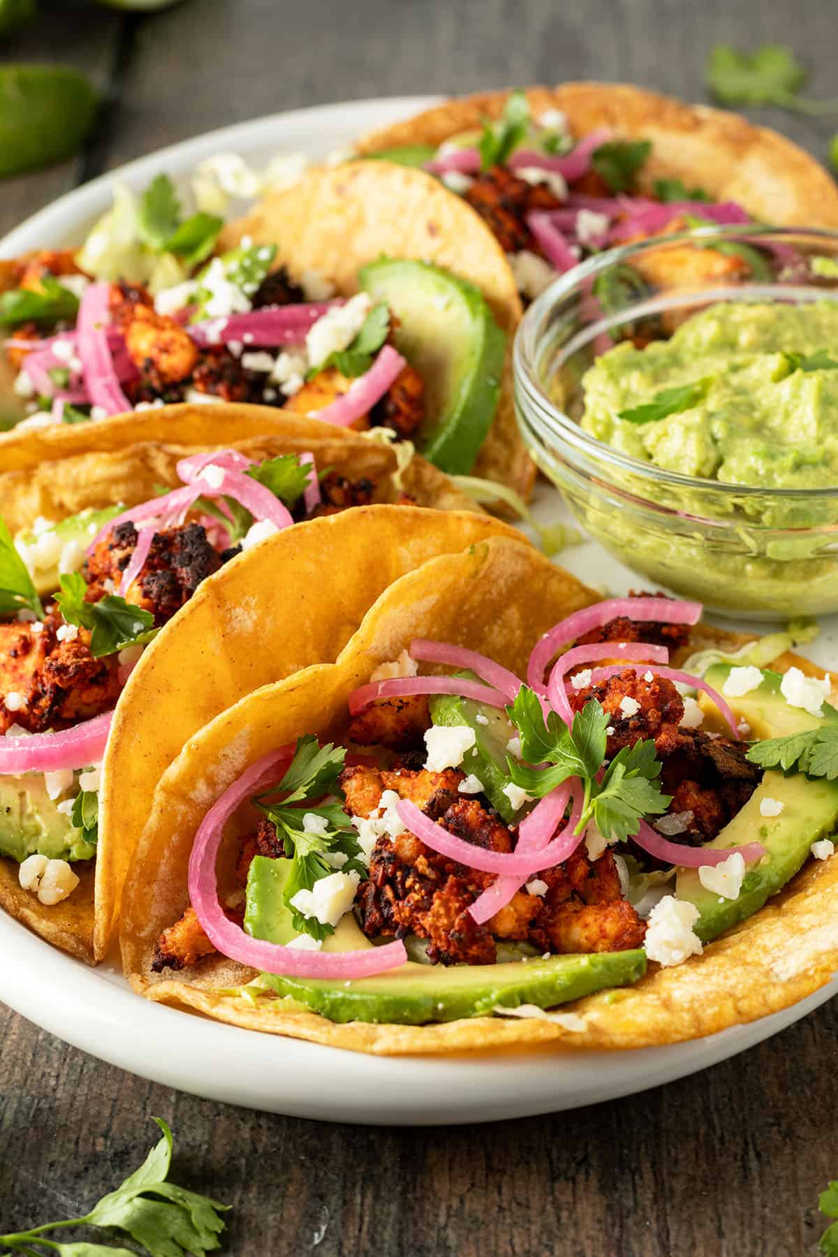 Ein Teller mit vegetarischen Tacos, die mit Tofu, Avocado und Zwiebeln gef&uuml;llt sind.