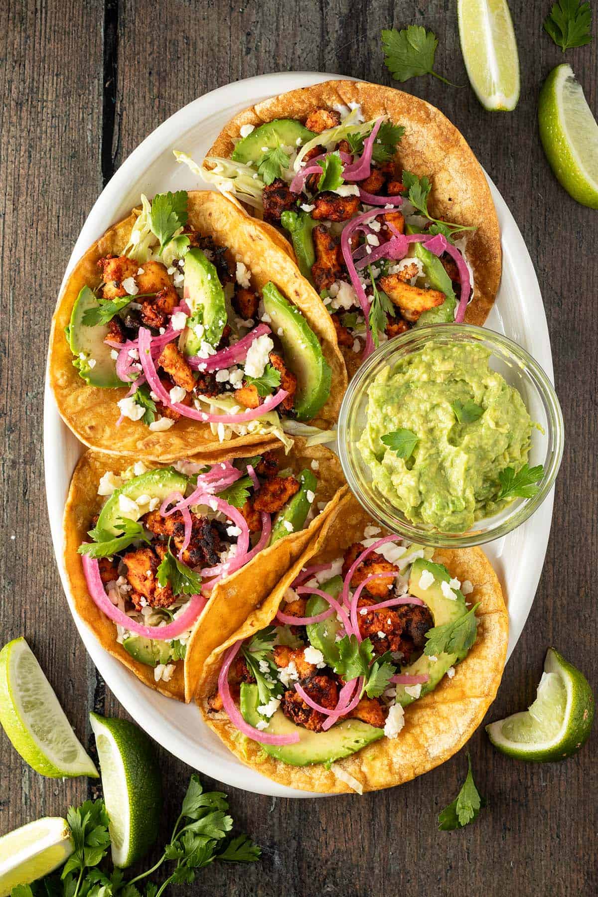 Vegetarische Tacos serviert auf einem Teller mit Guacamole und Limetten.