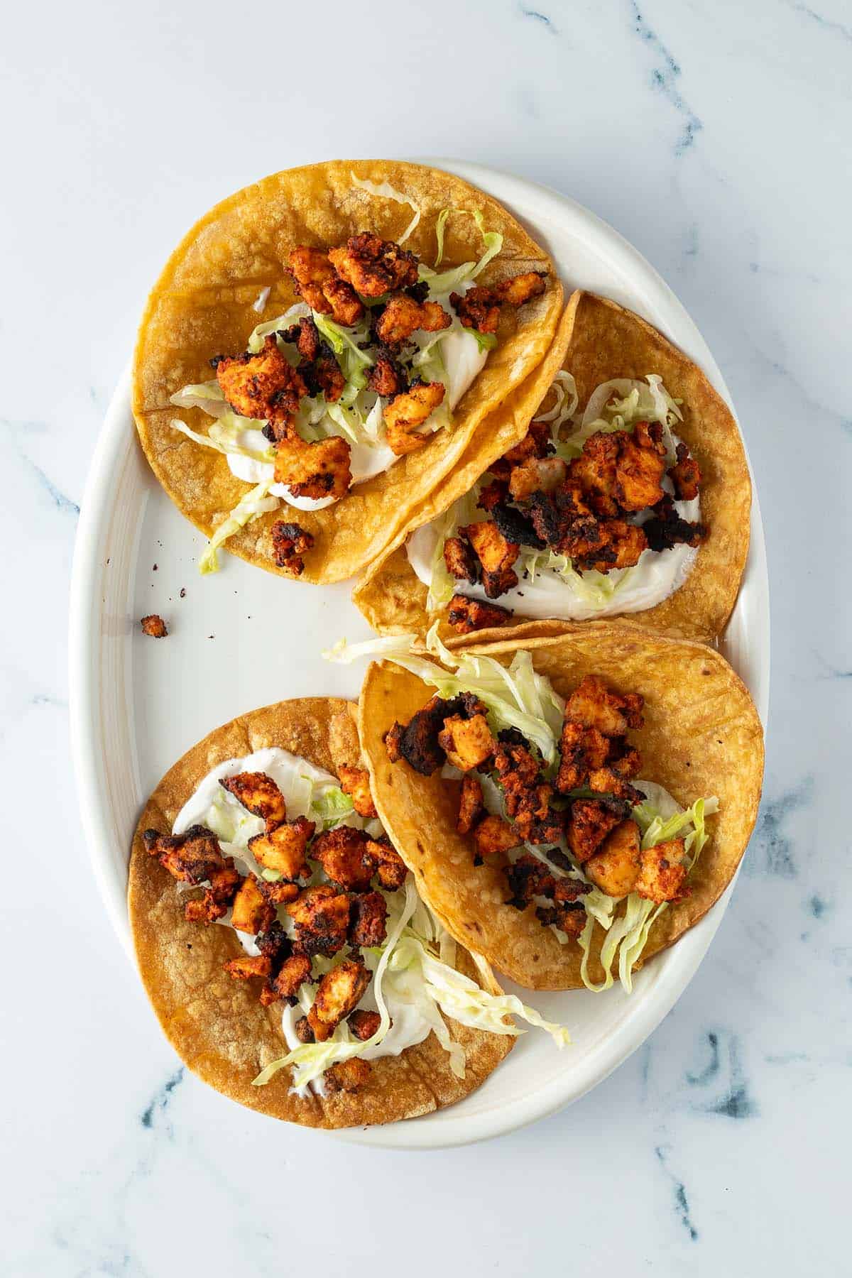 Knuspriger Tofu auf vier Tacos verteilt.