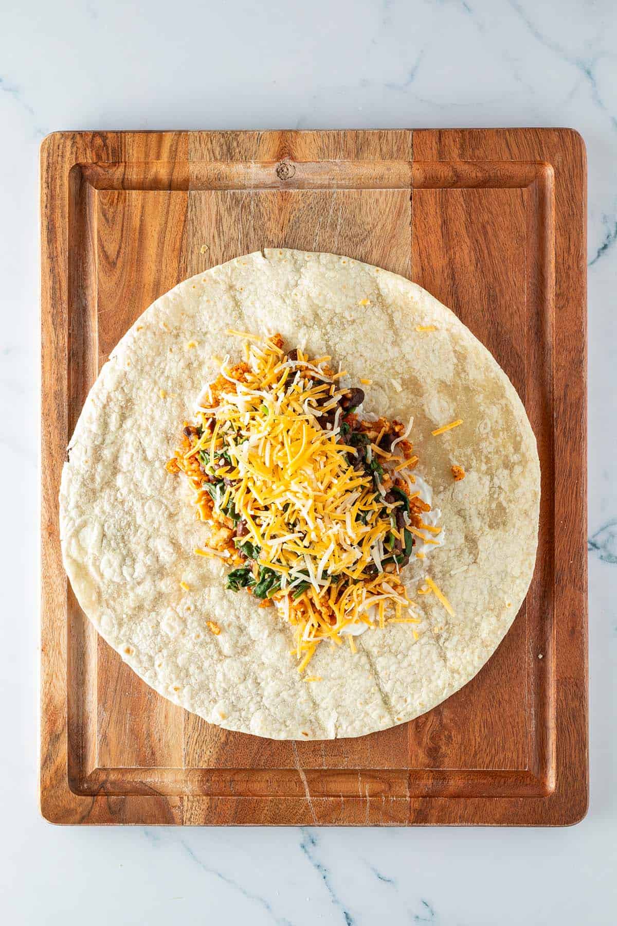 Tofu, Tomaten-Bohnen-Pfanne, K&auml;se und Schmand wurden in der Mitte von einem Tortilla gestapelt.