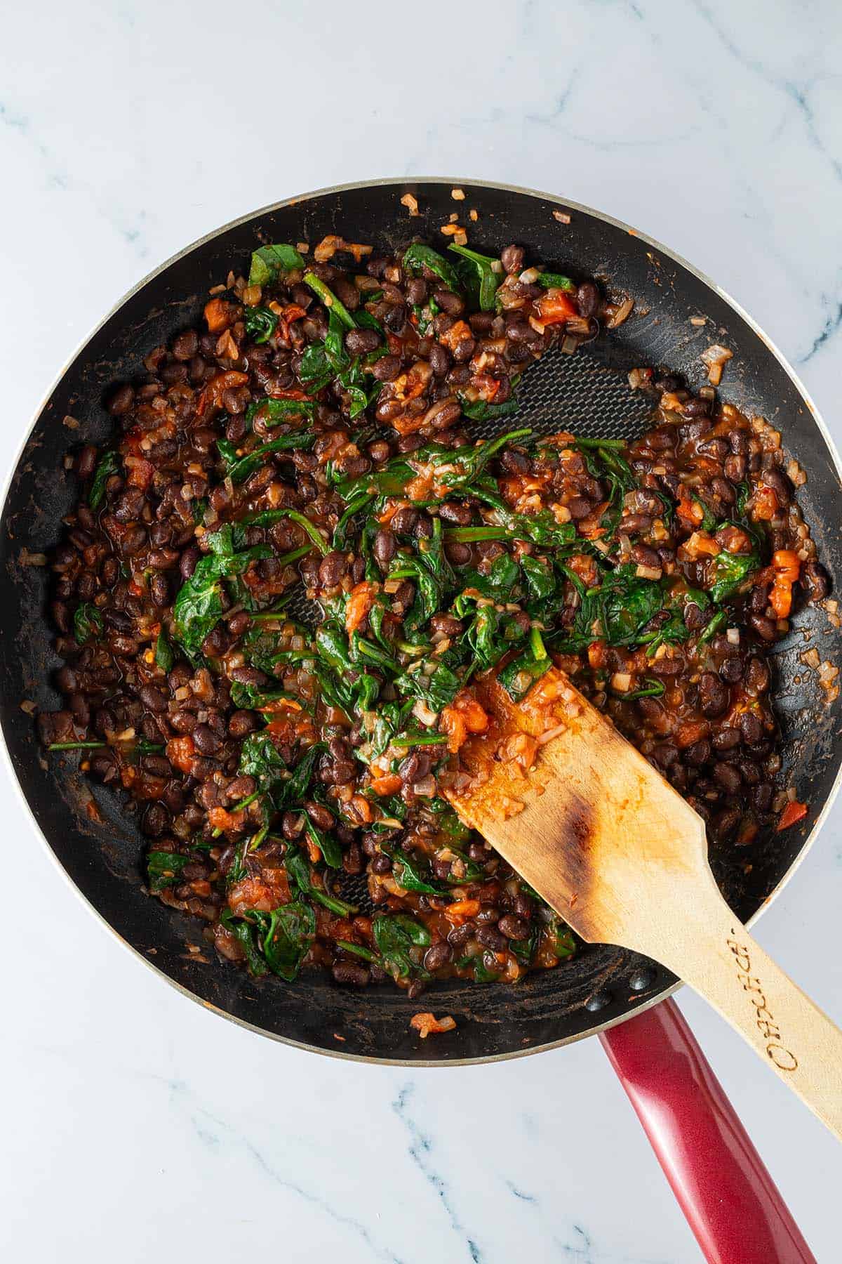 Fertige Bohnen-Spinat-Tomaten F&uuml;llung in einer gro&szlig;en Pfanne.