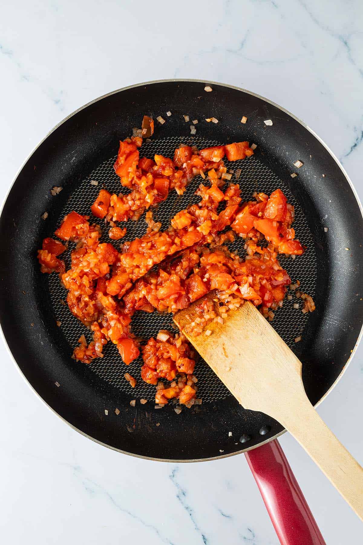 Tomaten und Schalotte werden in einer Pfanne angebraten.
