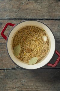 Ein Topf mit Wasser, Linsen, zwei Lorbeerbl&auml;tter, einer Knoblauchzehe und einem halben Suppenw&uuml;rfel drin.