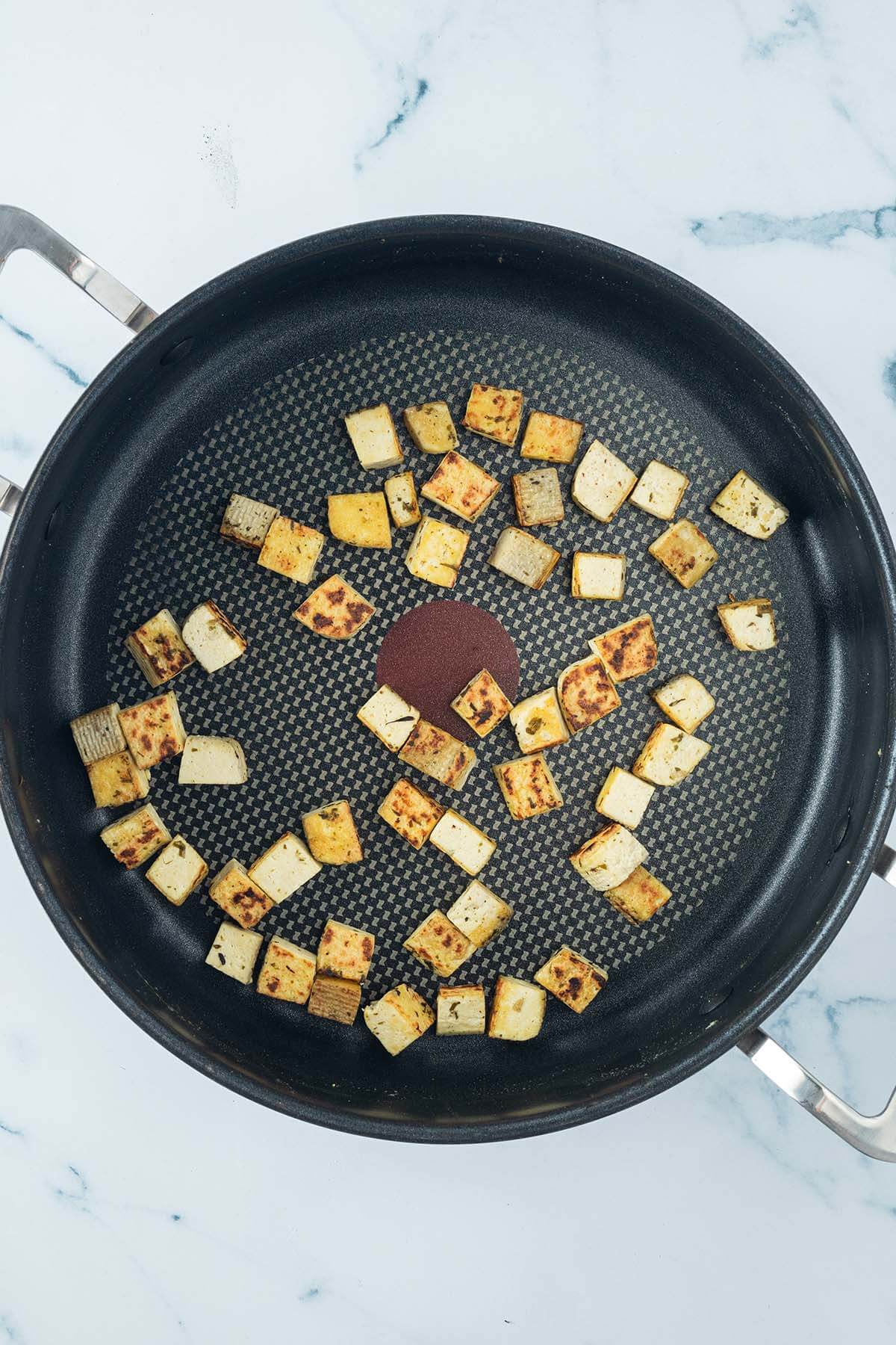 Knusprig gebratene Tofu-St&uuml;ckchen in einer gro&szlig;en Pfanne.