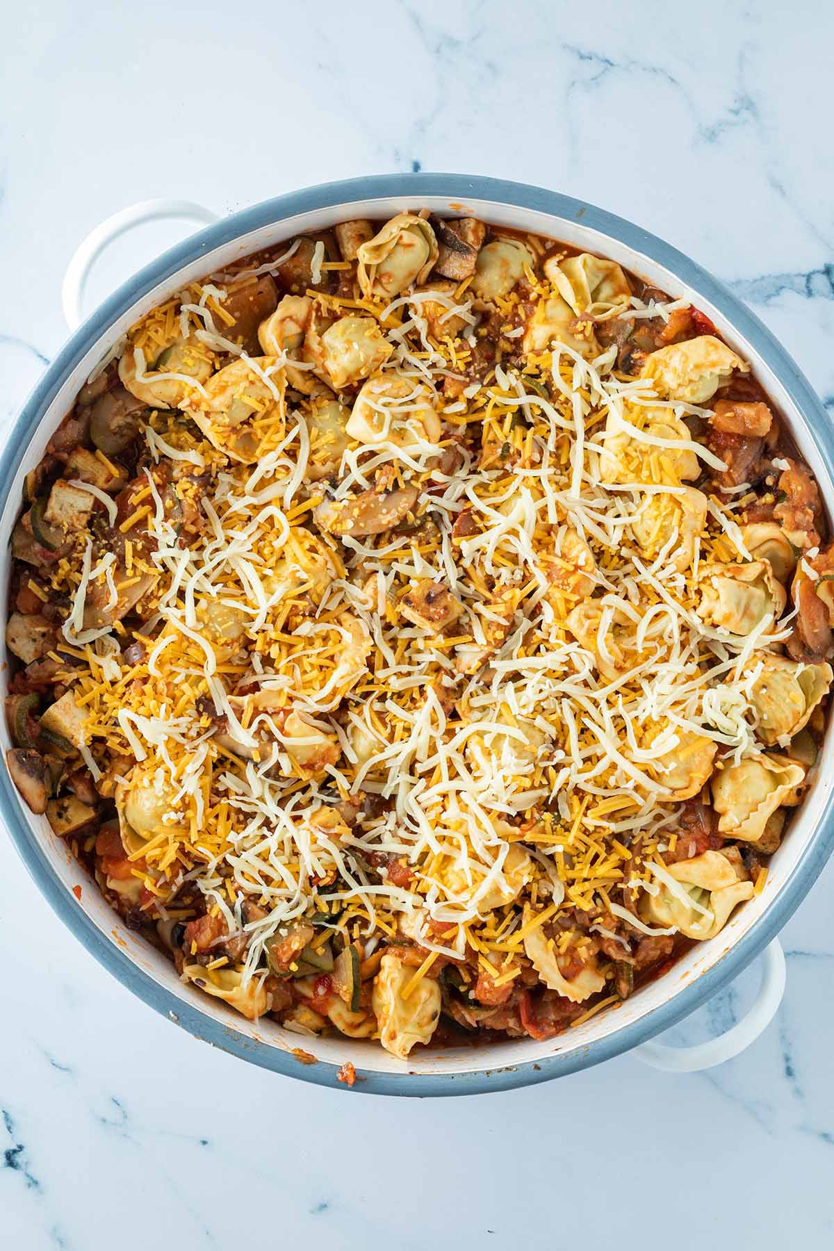 Tortellini Auflauf in einer Auflaufform vor dem &Uuml;berbacken, mit geriebenem K&auml;se auf der Oberfl&auml;che.