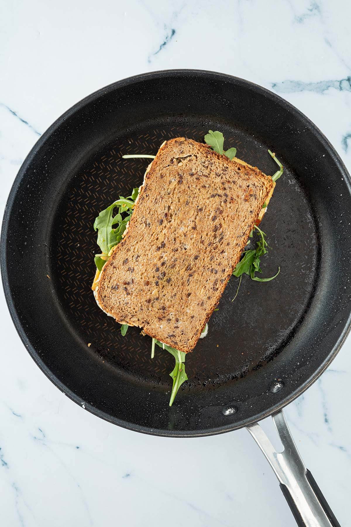 Sandwich wird in einer Pfanne angebraten.