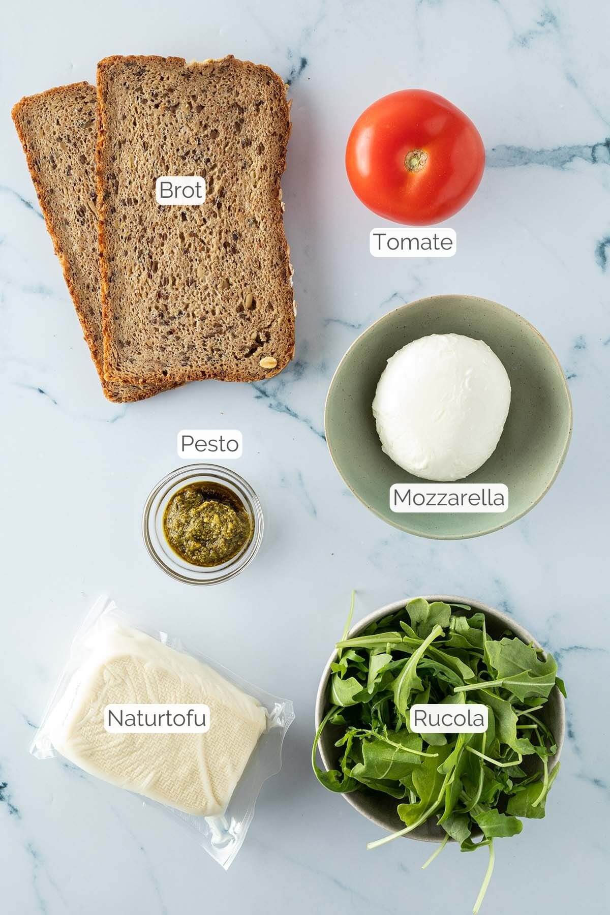 Foto aller Zutaten mit jeweiligen Textbeschriftungen, die f&uuml;r das Sandwich ben&ouml;tigt werden.
