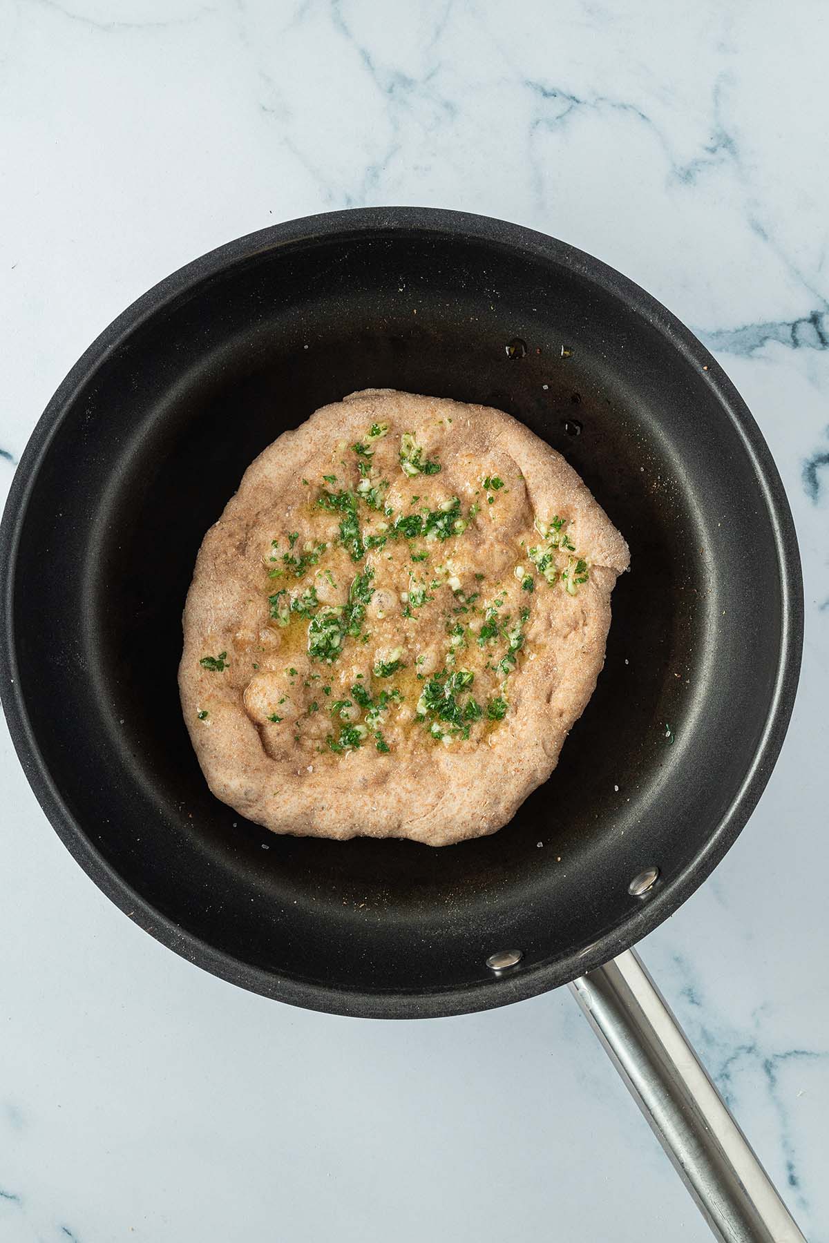 Ein Knoblauch-Kr&auml;uter Naan wird in einer Pfanne ausgebacken.