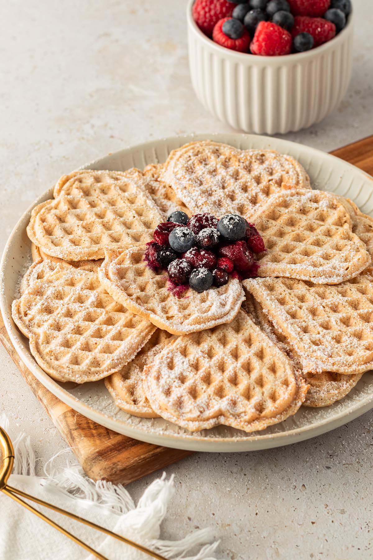 Ein Teller mit d&uuml;nnen, herzf&ouml;rmigen Waffeln, serviert mit frischen und hei&szlig;en Beeren mit Deko.