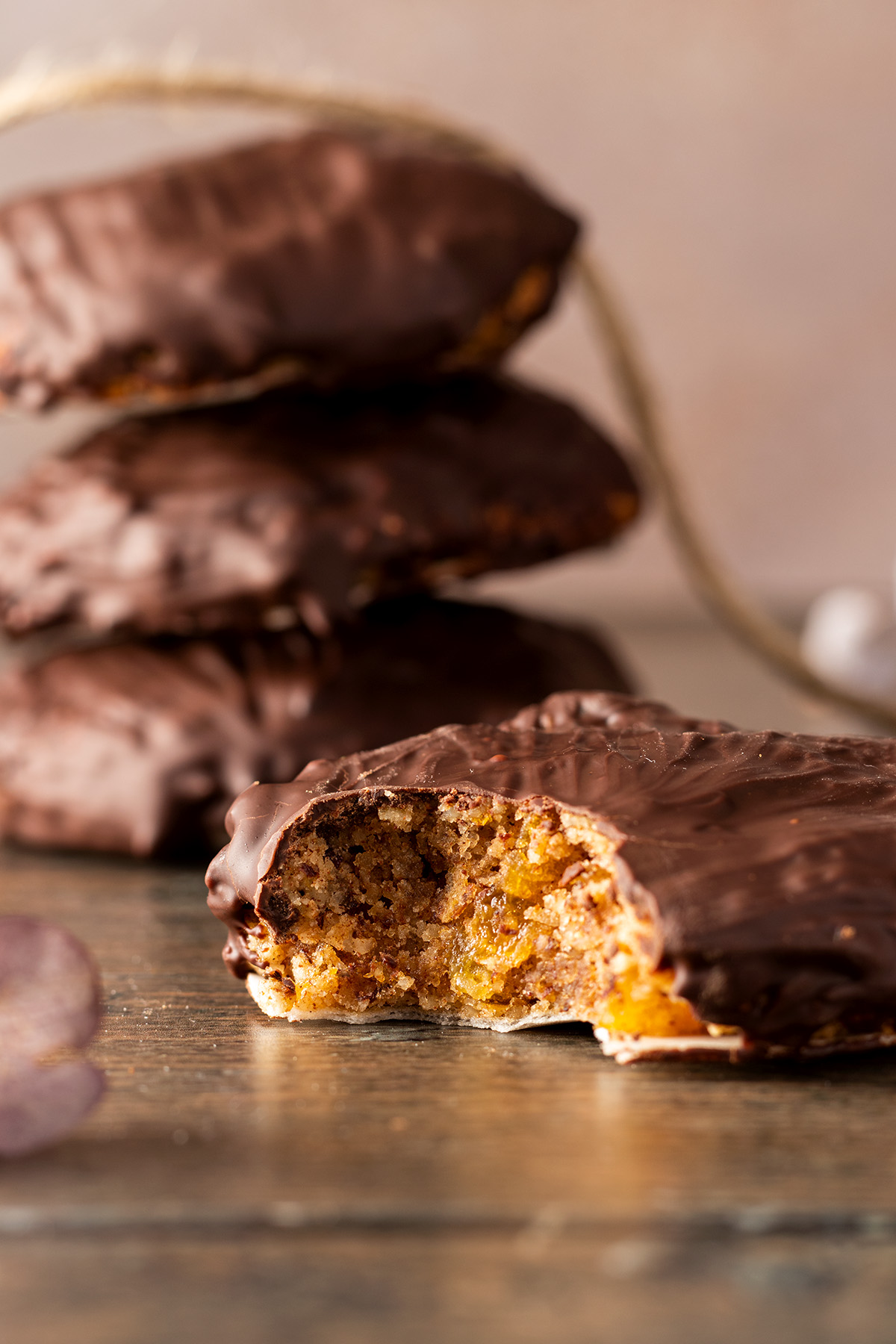 Angebissener weicher Elisenlebkuchen mit Schokoglasur, mehr Lebkuchen im Hintergrund.