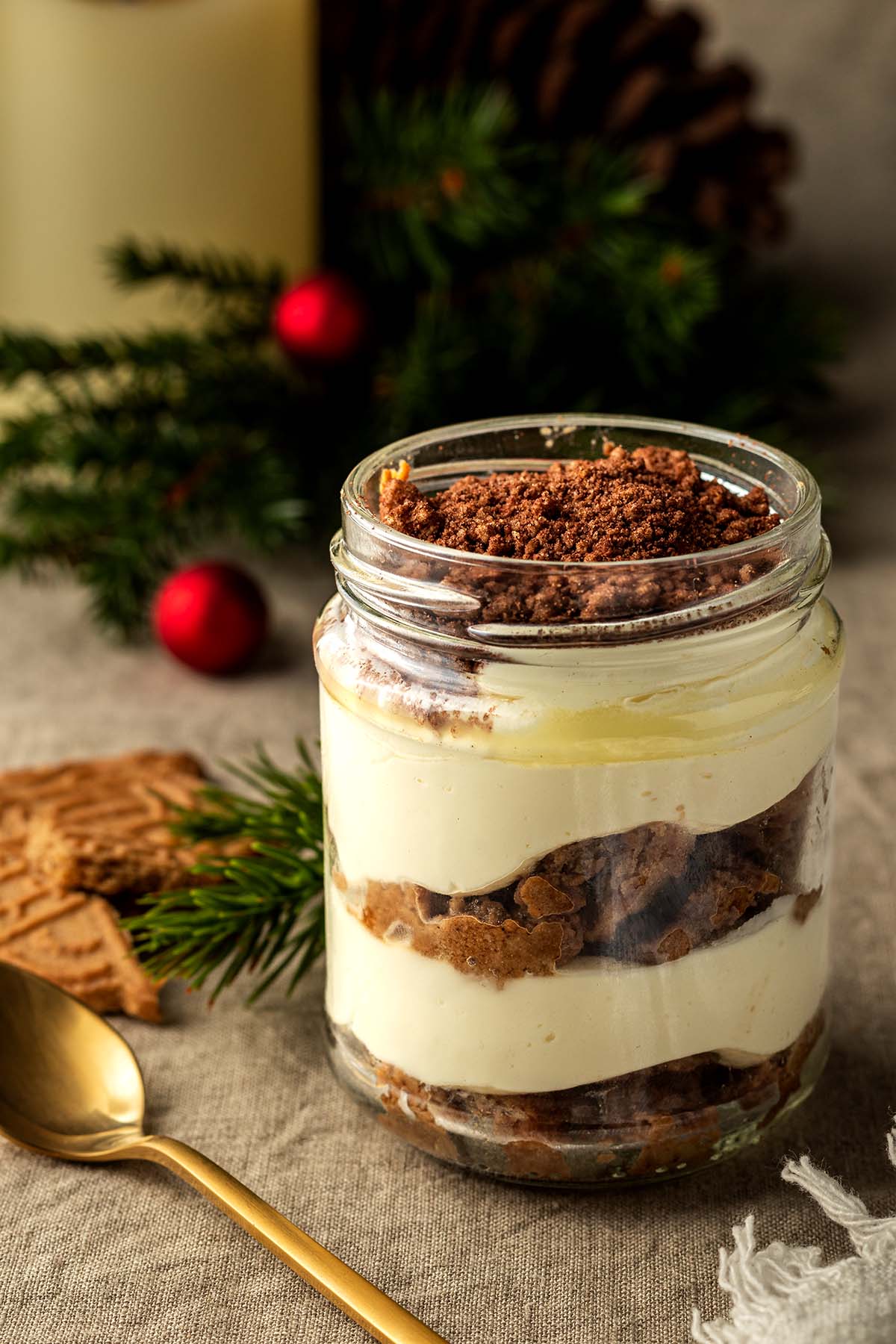 In einem kleinen Glas geschichtetes Spekulatius Tiramisu vor weihnachtlicher Deko.