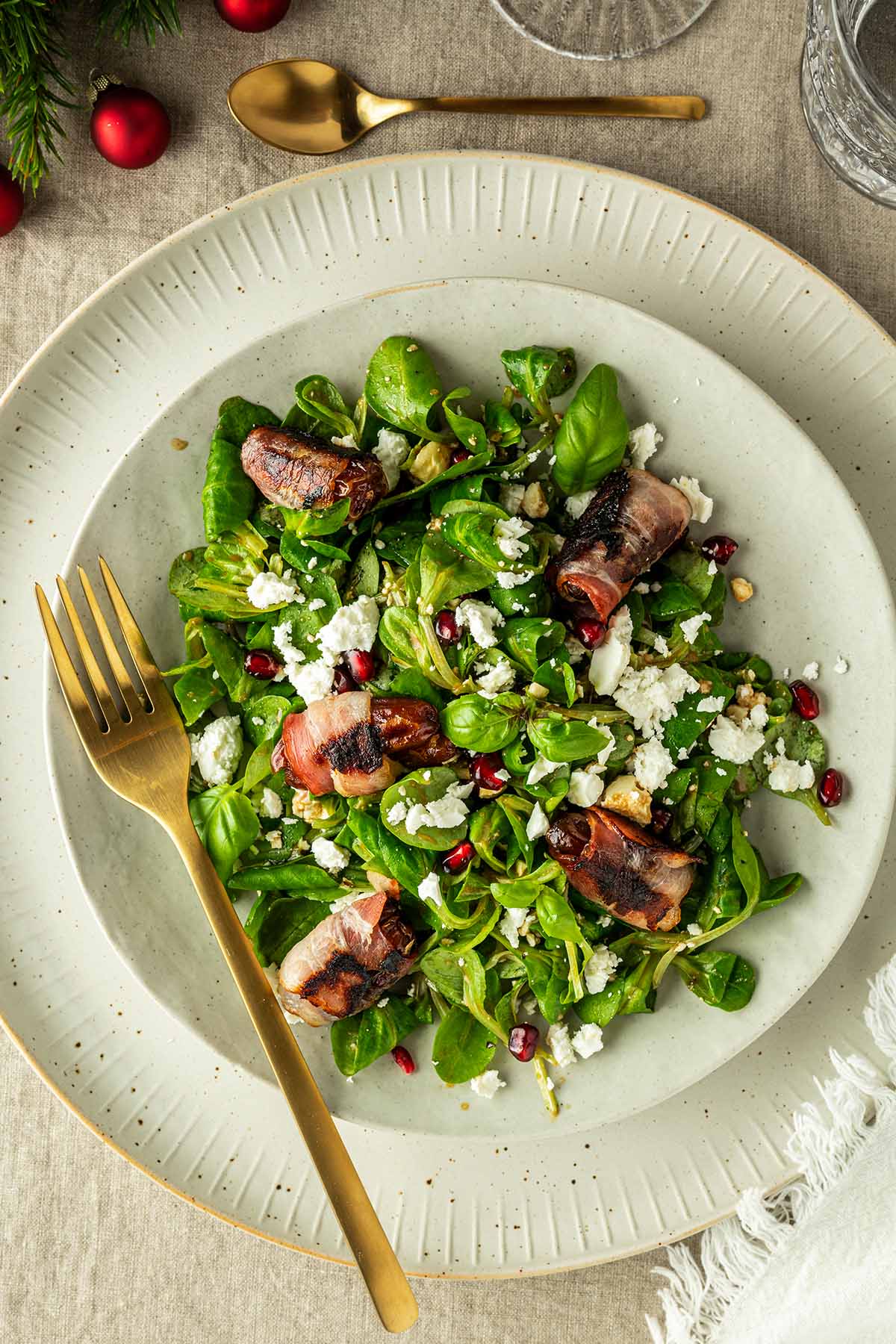 Ein Teller mit Feldsalat, Datteln im Speckmantel, zerbr&ouml;seltem Feta und Granatapfelkernen.