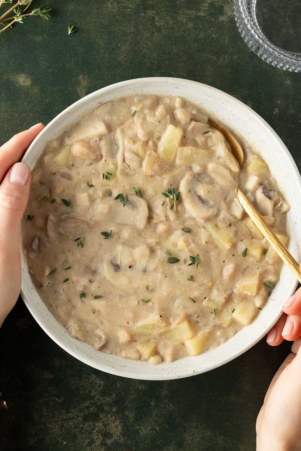 Wei&szlig;er Bohneneintopf mit Pilzen und Kartoffeln in einem tiefen Suppenteller.
