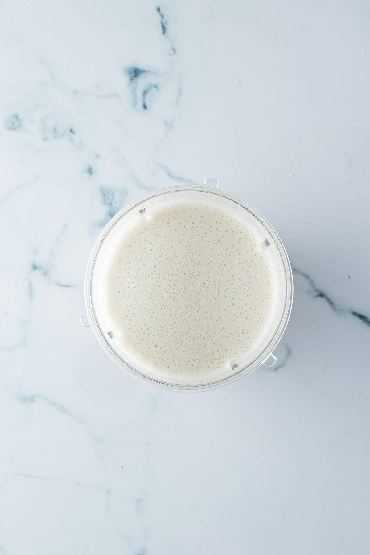 P&uuml;rierte Bohnen, Milch, Cashew Mischung in einem Mixbecher.