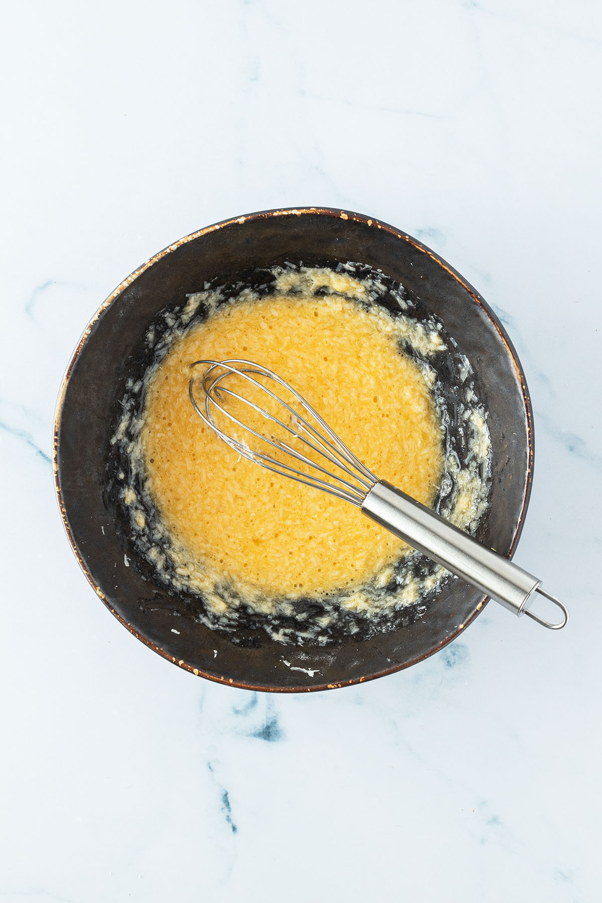 Ei und geriebener Parmesan verr&uuml;hrt in einer Sch&uuml;ssel.