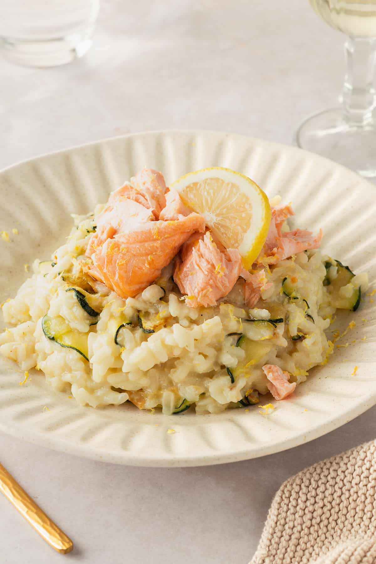Ein Teller mit cremigen Risotto mit Zitrone, Zucchini uns saftigem Lachsst&uuml;ckchen.