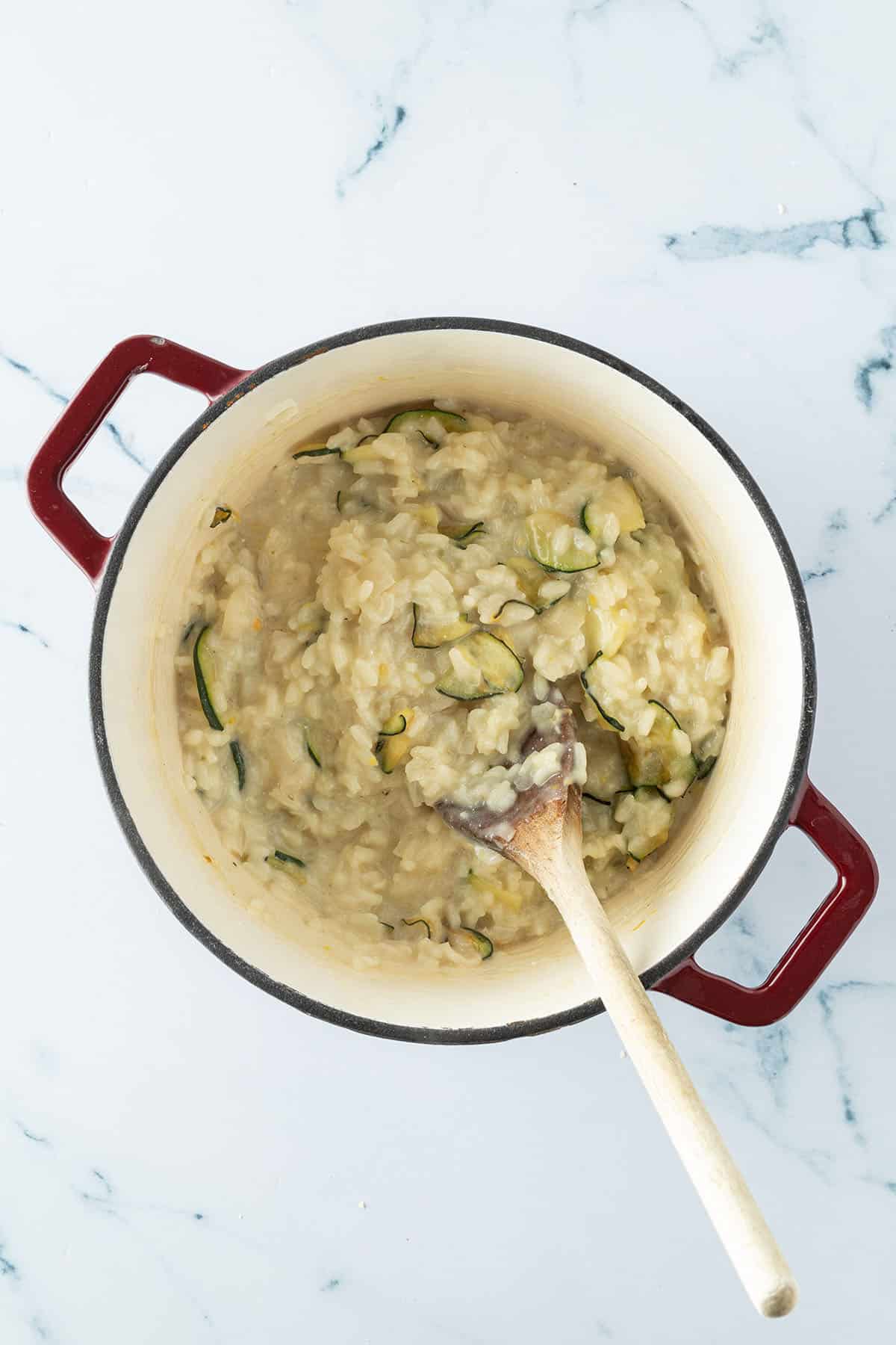 Cremiges Risotto in einem Topf mit den angebratenen Zucchinischeiben.
