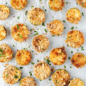 Knusprige Parmesan Zucchini Chips auf wei&szlig;em Backpapier.