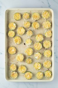 Panierte Zucchini Scheiben auf einem Backblech.