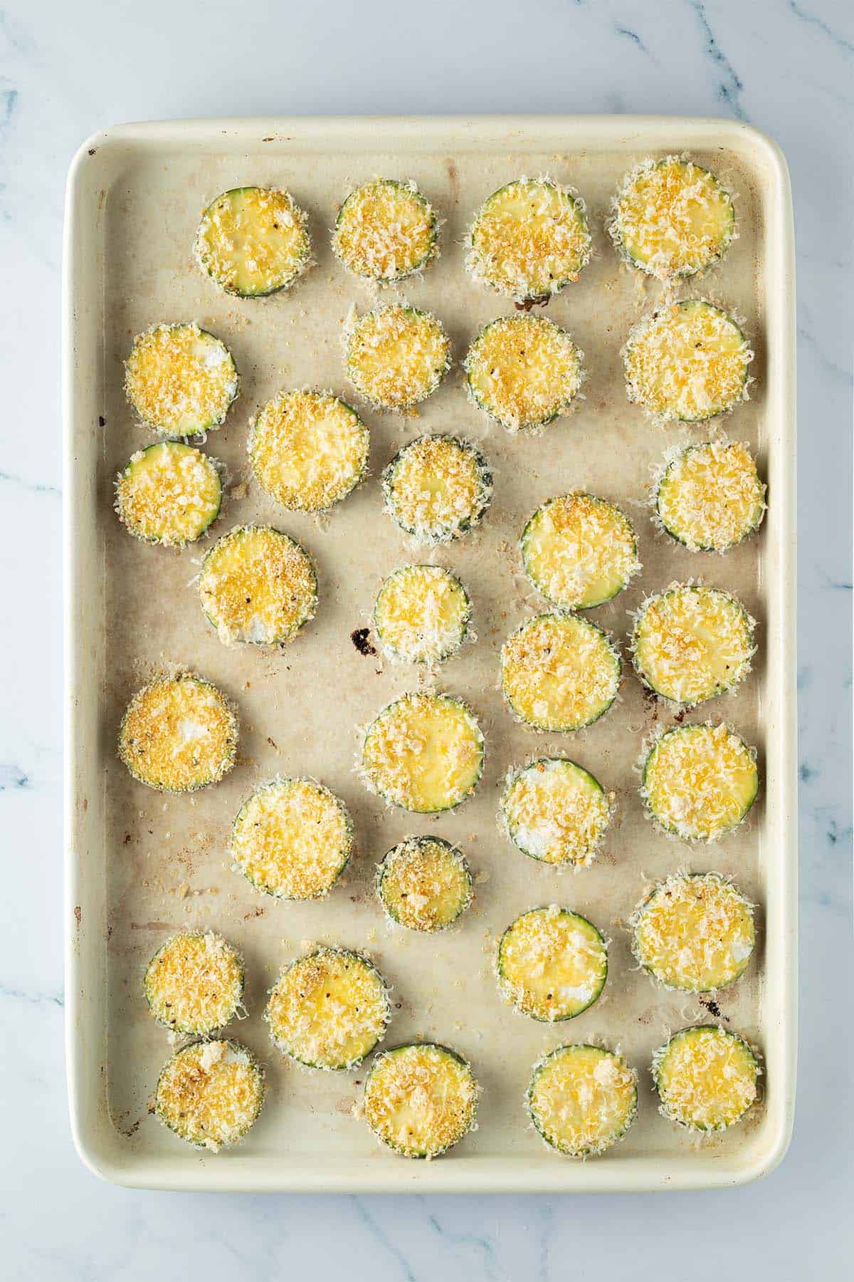 Panierte Zucchini Scheiben auf einem Backblech.