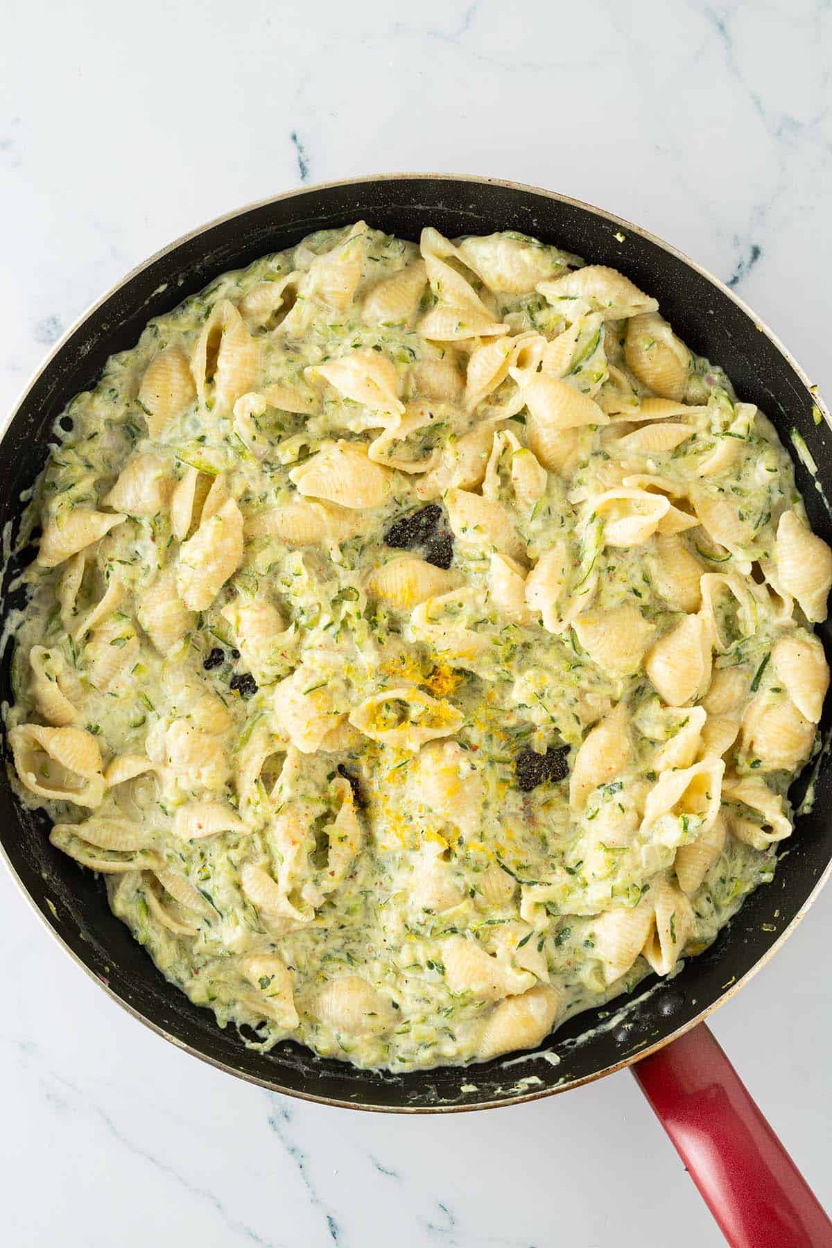 Eine gro&szlig;e Pfanne mit Pasta in cremiger Zucchini-Ricotta-Sauce mit Zitronenabrieb.