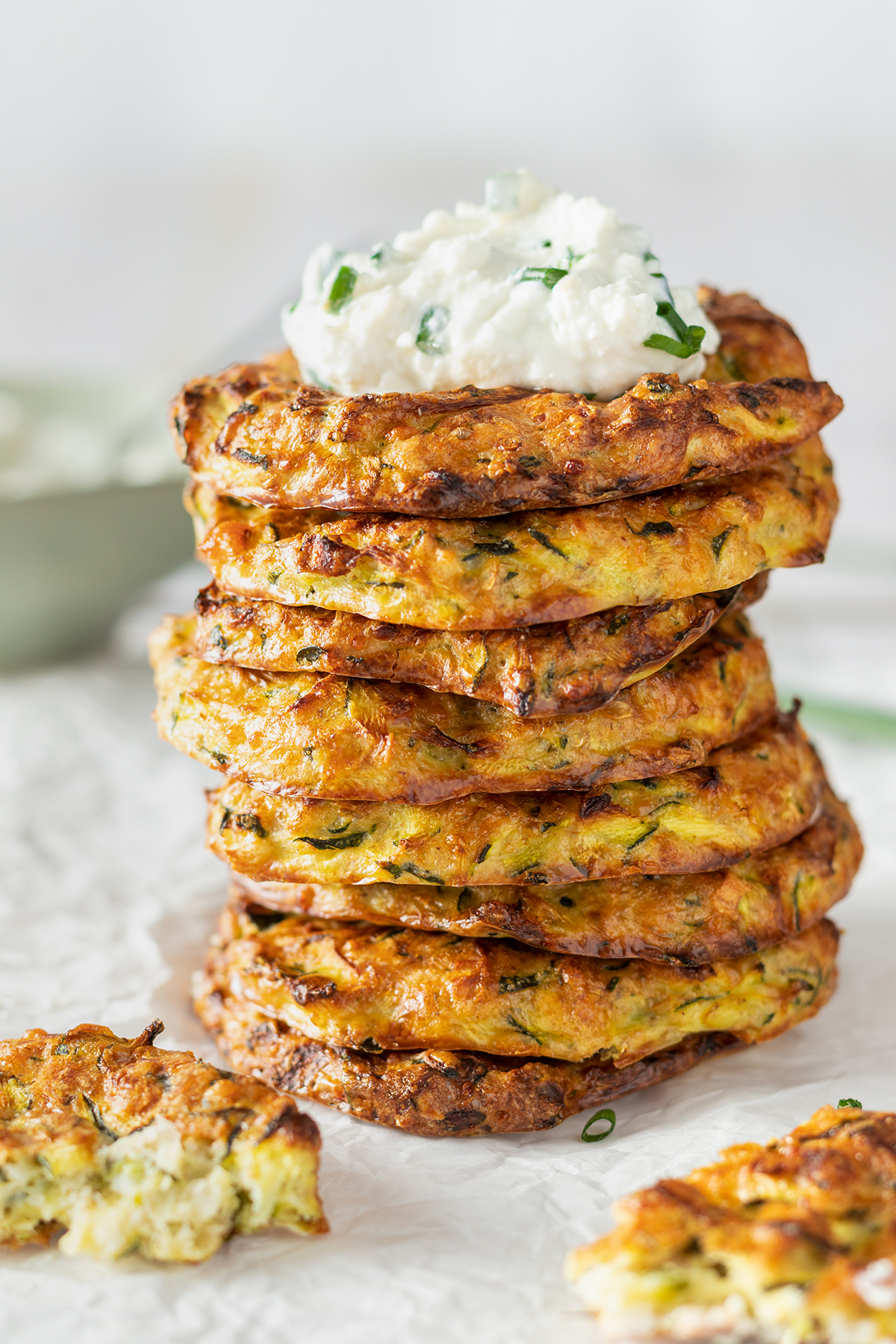 Stapel aus Zucchinipuffer mit Feta Dip oben drauf.