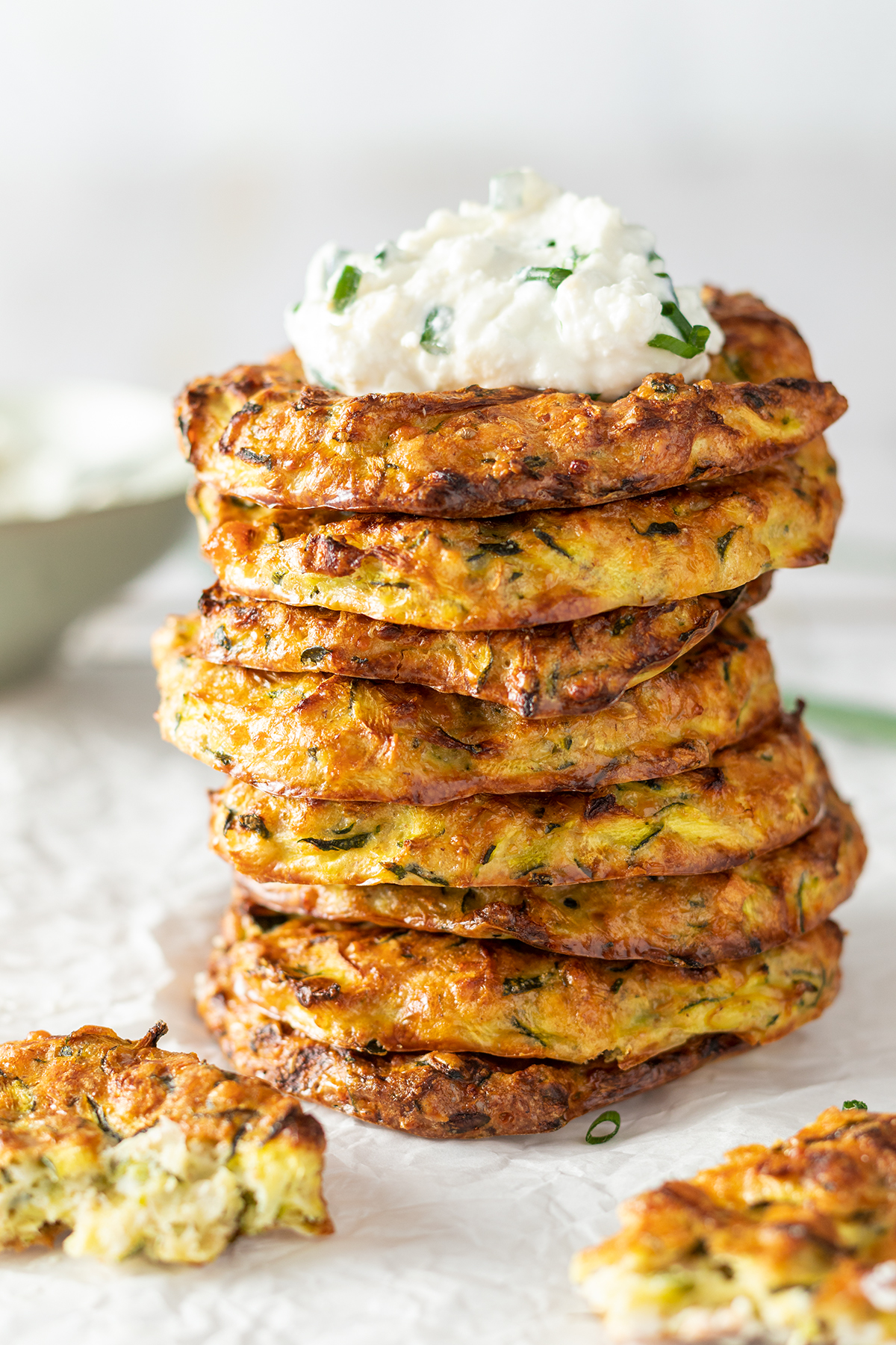 Stapel aus Zucchinipuffer mit einem Keks cremigen Feta-Dip drauf.